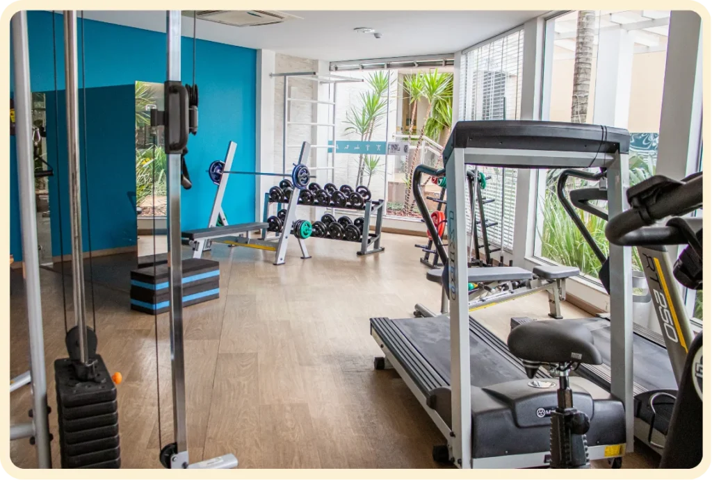 Academia moderna com esteiras, pesos e parede azul vibrante.