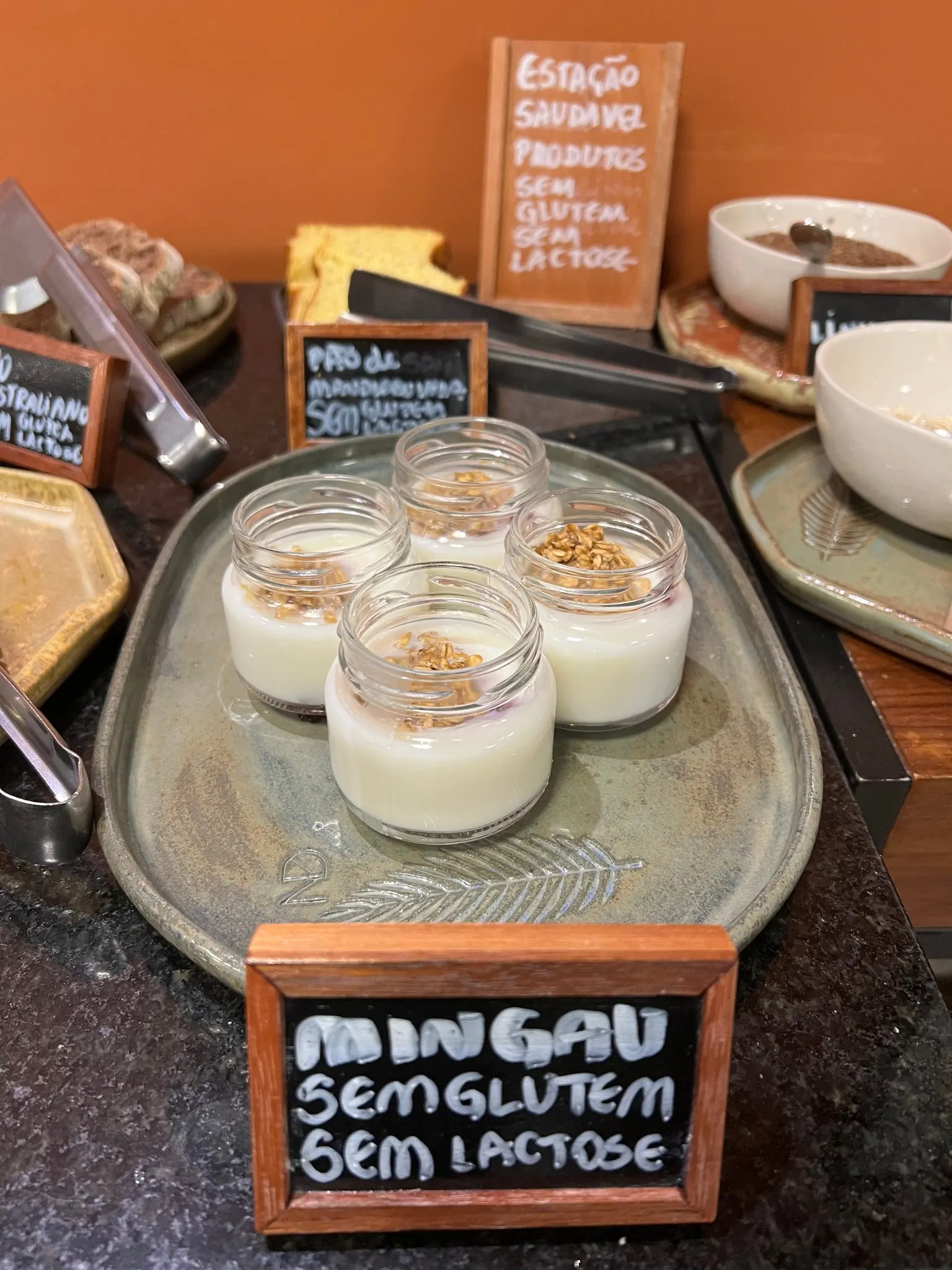 Experiências 6 Mesa de café da manhã com potes de vidro e placa escrita: mingau zero lactose.