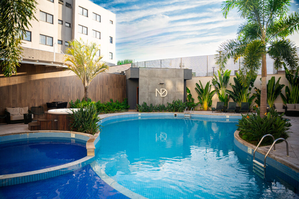 Piscina rodeada por plantas e edifícios.