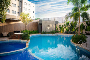 Piscina rodeada por plantas e edifícios.