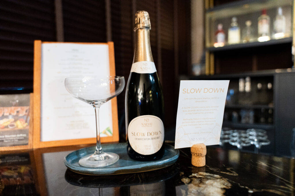 Hotel Nadai em celebra 45 anos com lançamento do Ateliê Nadai by Nair e da exposição Almas do Iguaçu 1 Champanhe e taça em bar elegante, na celebração de 45 anos do Hotel Nadai em Foz do Iguaçu.