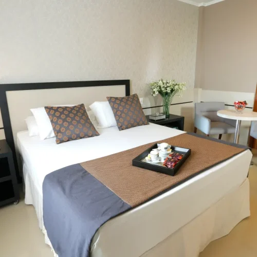 Acomodações 16 imagem mostra espaço geral da suíte família com cama de casal, bandeja de café da manhã e itens do quarto.